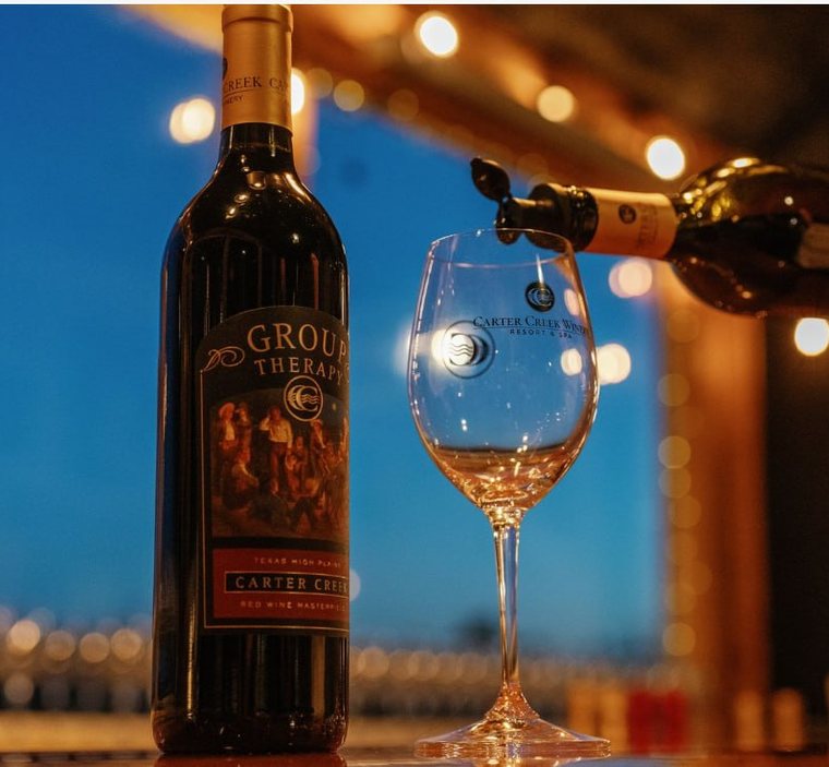 Carter Creek Winery's Group Therapy red wine poured into a branded glass at twilight